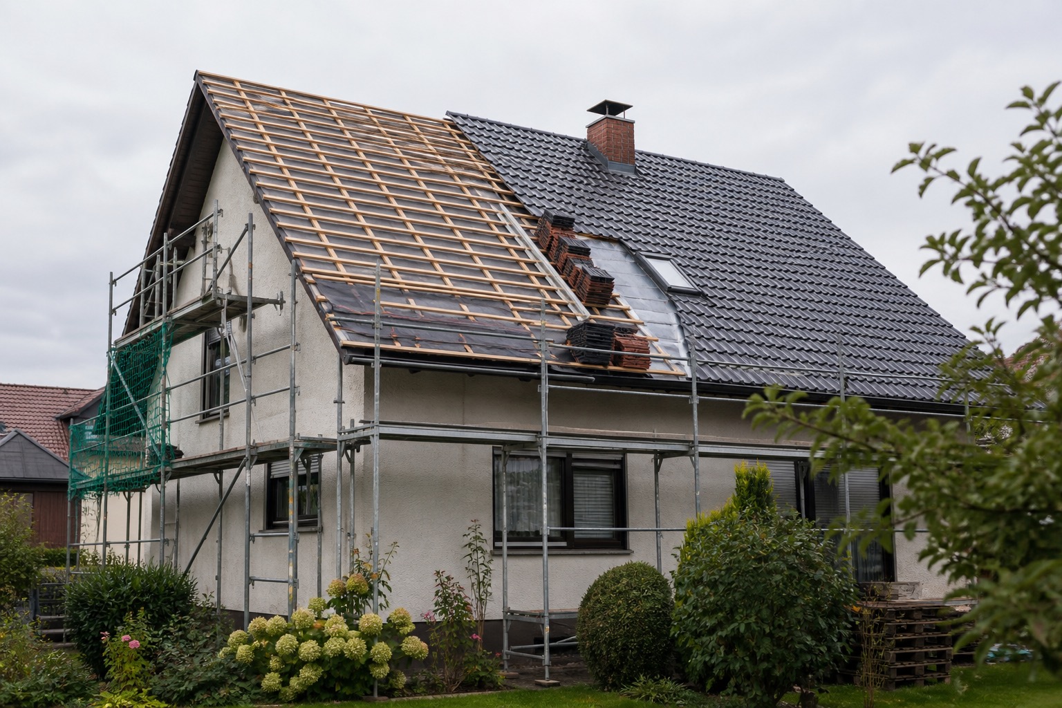 Wohnhaus während einer Dachsanierung mit Gerüst, freigelegter Lattung und neuer Dacheindeckung
